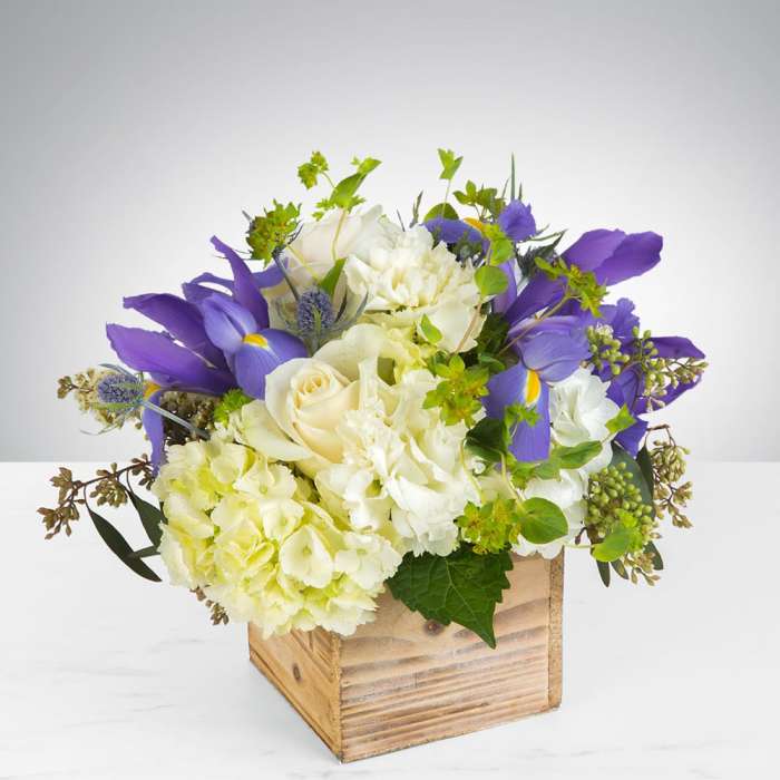 Low wooden box arrangement with white roses and hydrangeas accented by purple irises