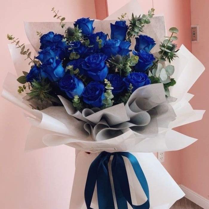 Bouquet of blue roses wrapped in white paper with a blue ribbon