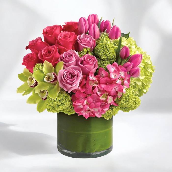 Pink roses and tulips arranged in a green glass vase