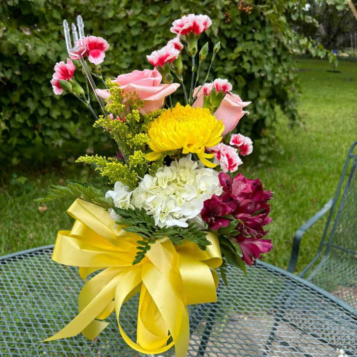 Bouquet of pink roses, yellow chrysanthemum, white hydrangea, and magenta alstroemeria in a glass vase
