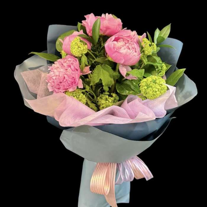 Pink peony bouquet wrapped in pastel paper with ribbon