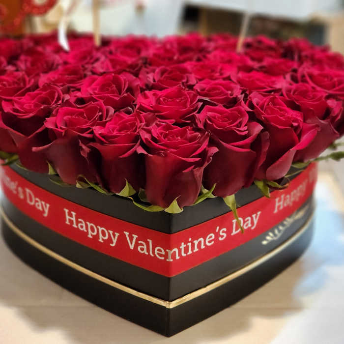 Heart-shaped box of red roses with a Valentine’s Day ribbon