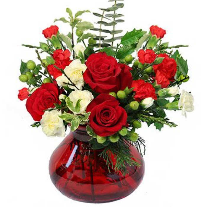 Red and white rose arrangement in a red glass vase