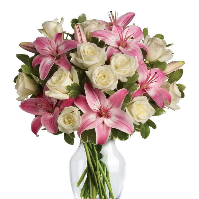 Pink lilies and white roses arranged in a clear glass vase