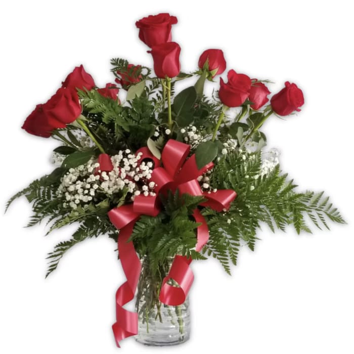 Red roses in a glass vase with baby's breath and a red ribbon