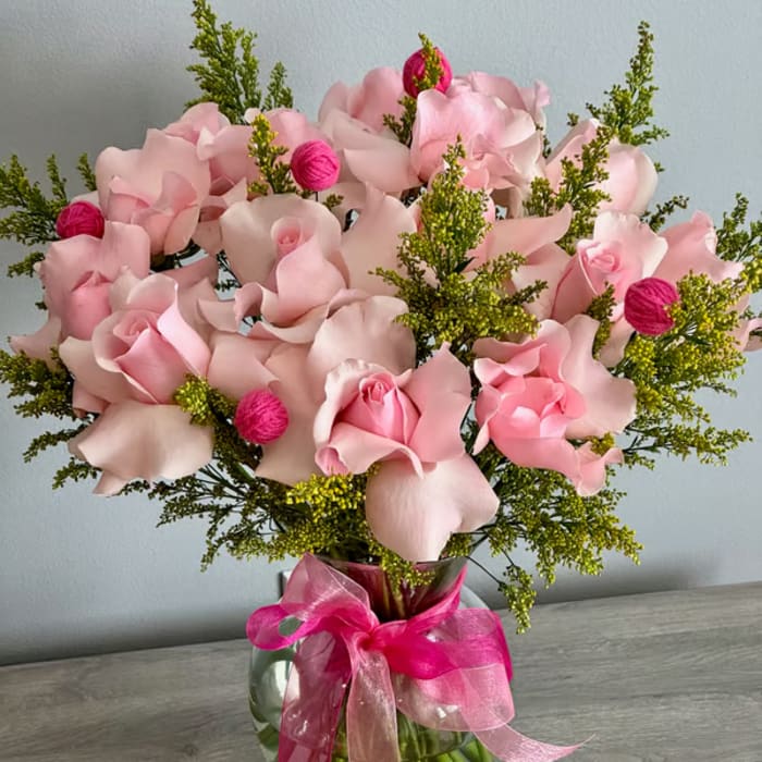 Pink rose bouquet in a glass vase with a bright ribbon
