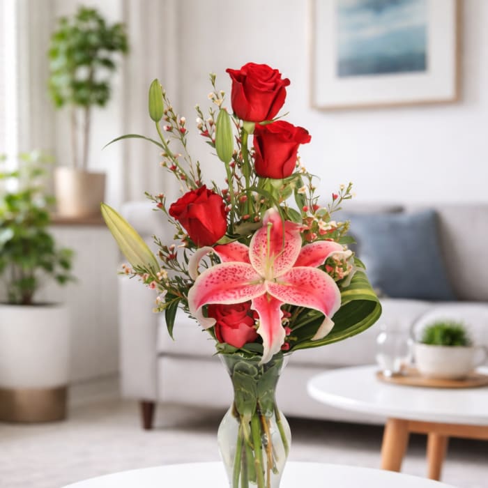 Red roses and pink lilies arranged in a clear glass vase