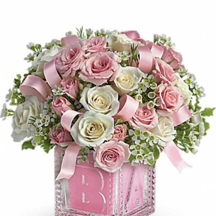 Pink and white roses arranged in a decorative box with ribbon accents