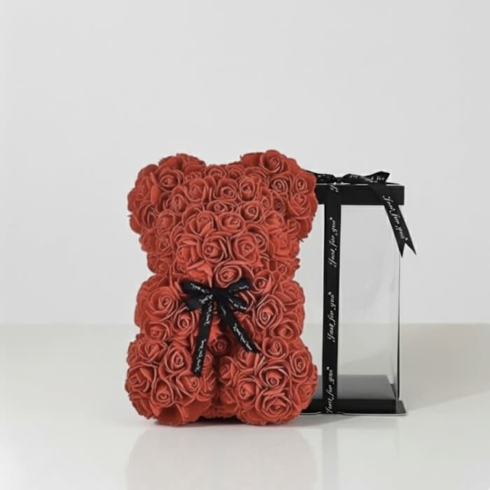 Red rose teddy bear beside a black gift box with ribbon