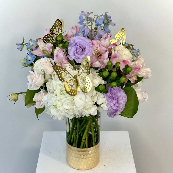 Bouquet of pastel flowers in a glass vase with butterfly picks
