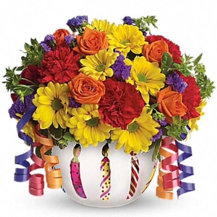 Colorful bouquet of roses, daisies, and carnations in a white vase with ribbons