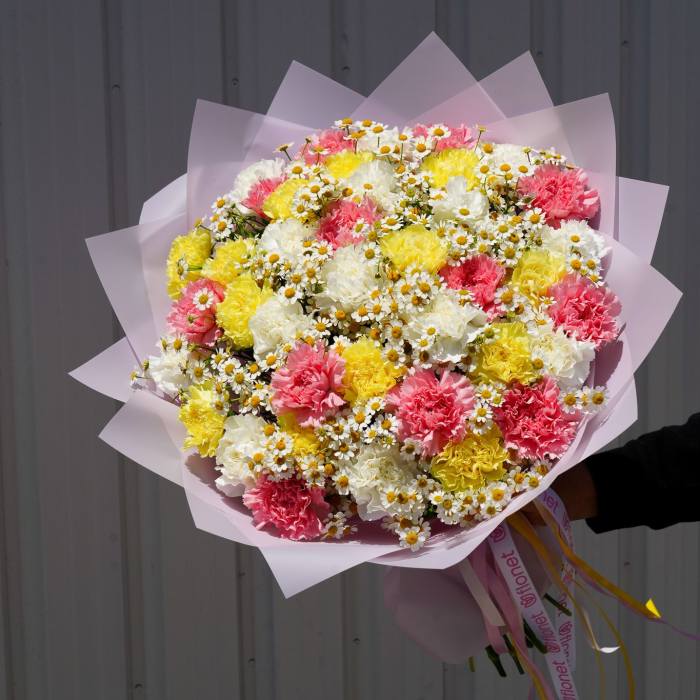 Large bouquet of pink, yellow, and white carnations with tiny daisies