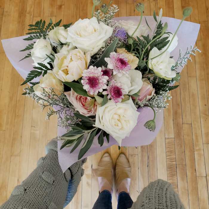 Handheld bouquet of white and blush roses with pink daisies in lavender wrap