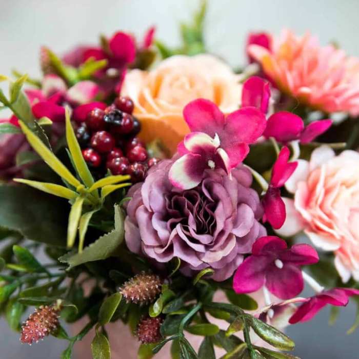Pink and peach floral arrangement in a pale vase