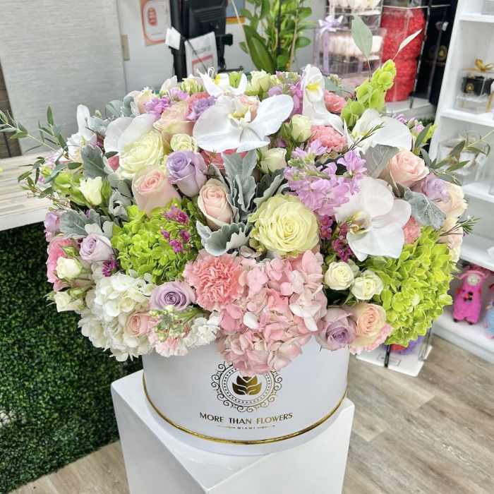 Large pastel arrangement of roses, orchids, hydrangeas and carnations in a white hatbox