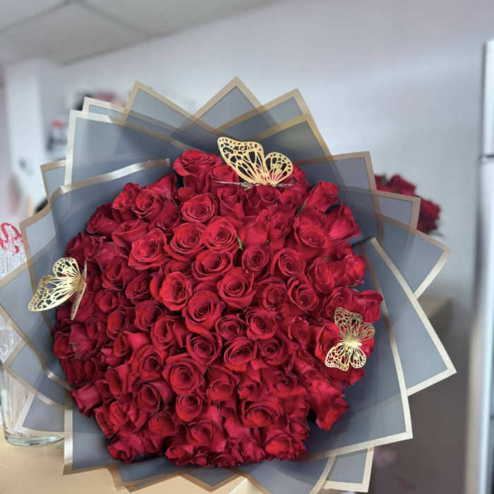 Large bouquet of red roses wrapped in gray paper with gold butterfly accents