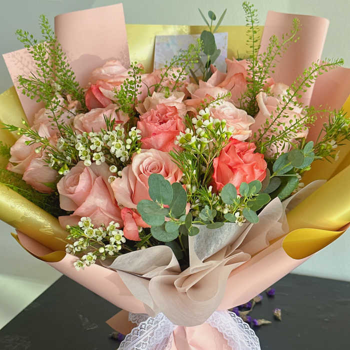 Pink rose bouquet wrapped in blush paper with lace ribbon