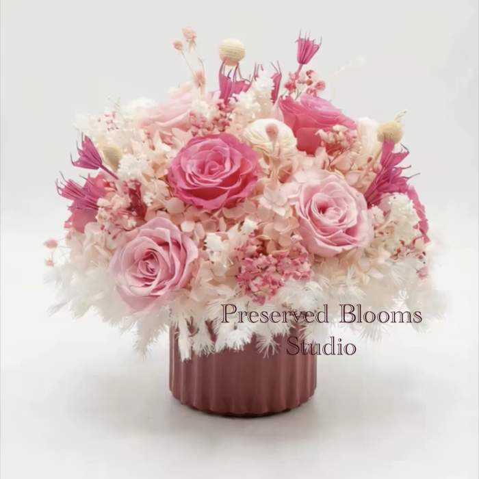 Low pink and white preserved flower arrangement with roses in a mauve ceramic pot