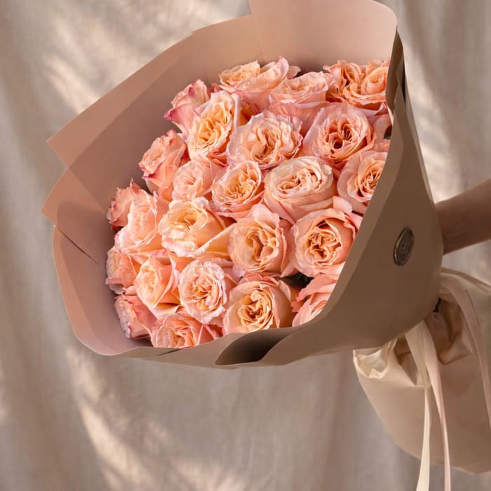Bouquet of peach roses wrapped in beige paper