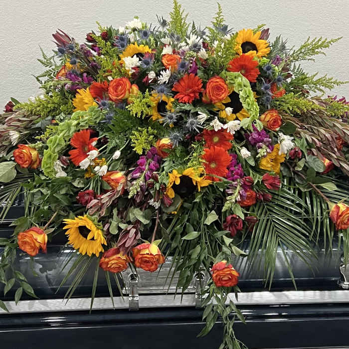 Large floral casket spray with sunflowers, roses, and mixed blooms