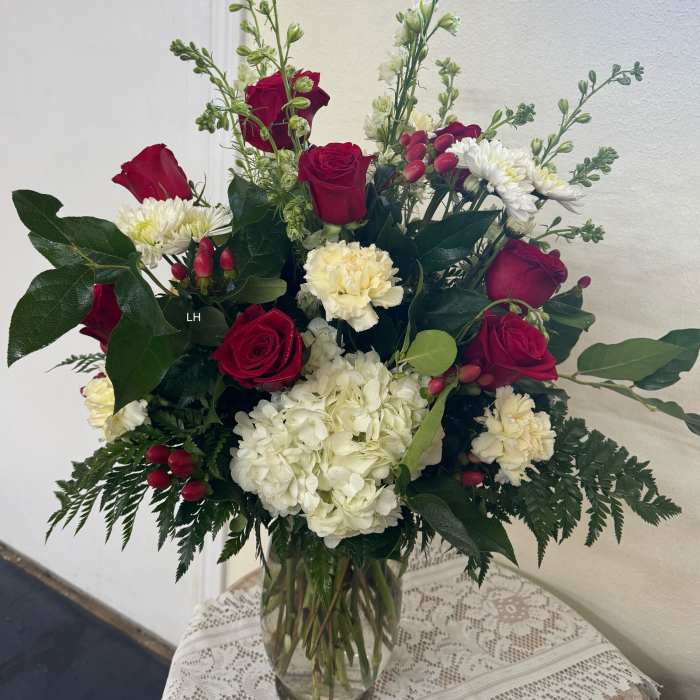 Red roses and white flowers in a clear glass vase