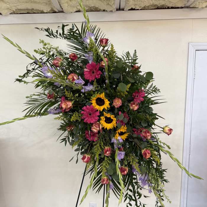 Large standing floral spray with sunflowers, pink gerberas, and roses