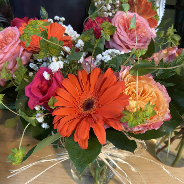 Mixed bouquet with orange gerbera daisies and pink roses in a glass vase