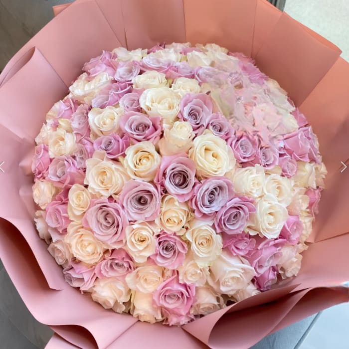 Large bouquet of pink, lavender, and cream roses wrapped in pink paper