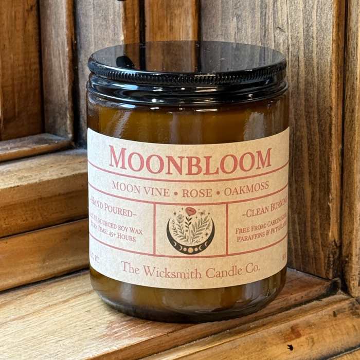 Amber candle jar with a black lid and labeled Moonbloom scent