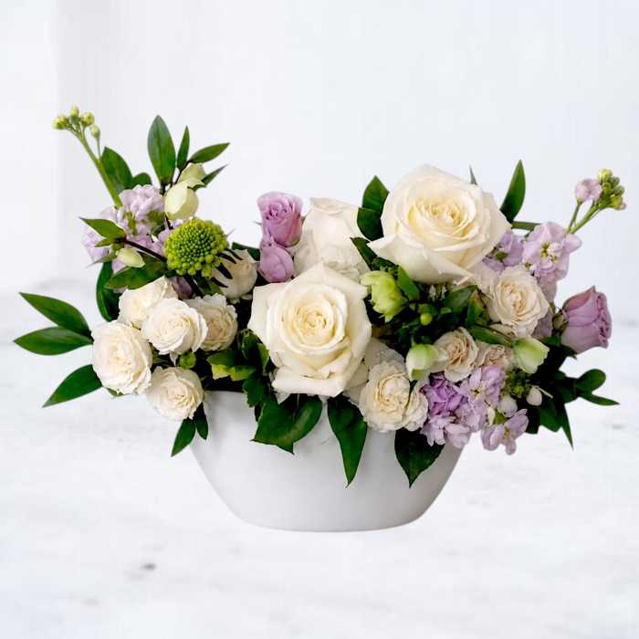 White and lavender roses arranged in a white bowl vase