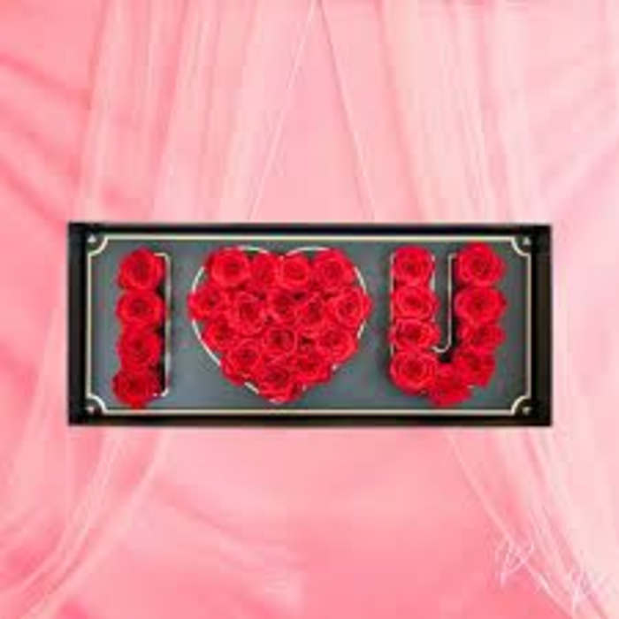 Red roses arranged in an "I ♥ U" display on a pink background