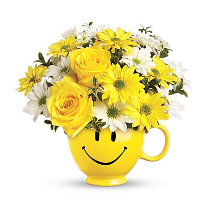 Yellow and white flowers arranged in a smiley-face mug