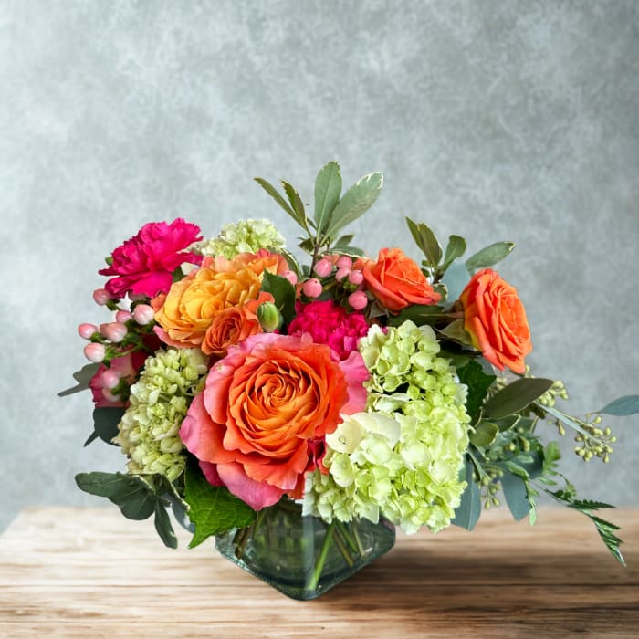 Orange roses and green hydrangeas in a glass vase