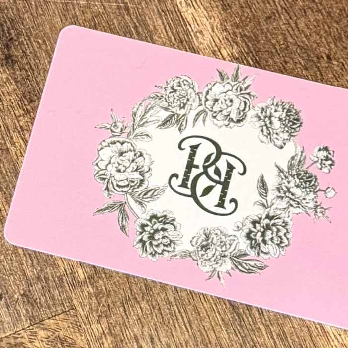 Pink card with a floral wreath and monogram