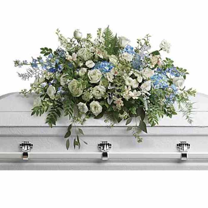 White and blue floral casket spray on a white casket