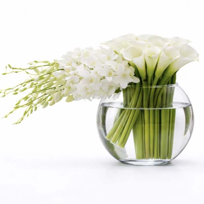 White calla lilies and orchids in a clear glass bowl vase