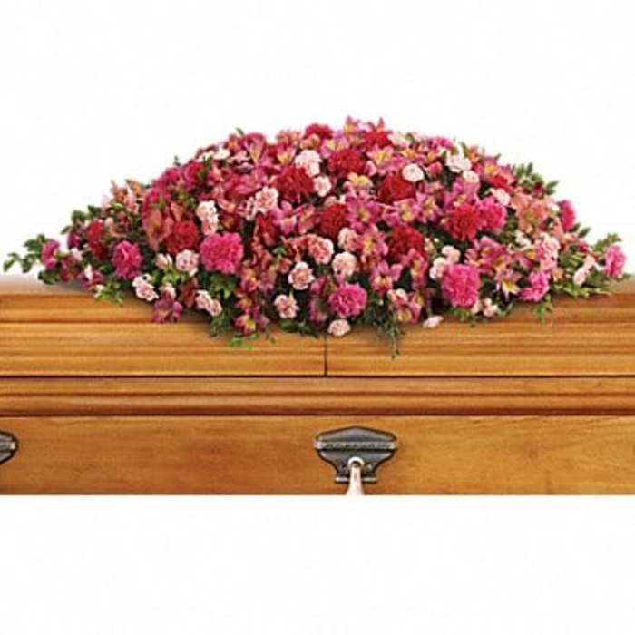 Pink and red floral casket spray on a wooden coffin