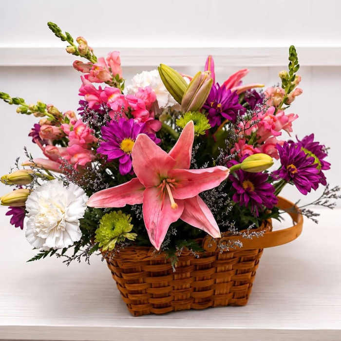 Basket arrangement with pink lilies, purple daisies, and white carnations