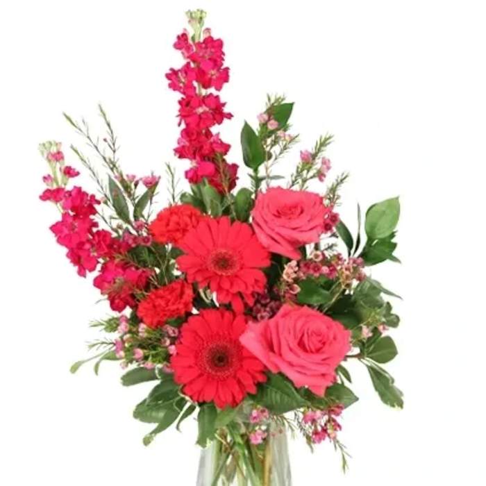 Pink and red mixed flower arrangement in a clear glass vase