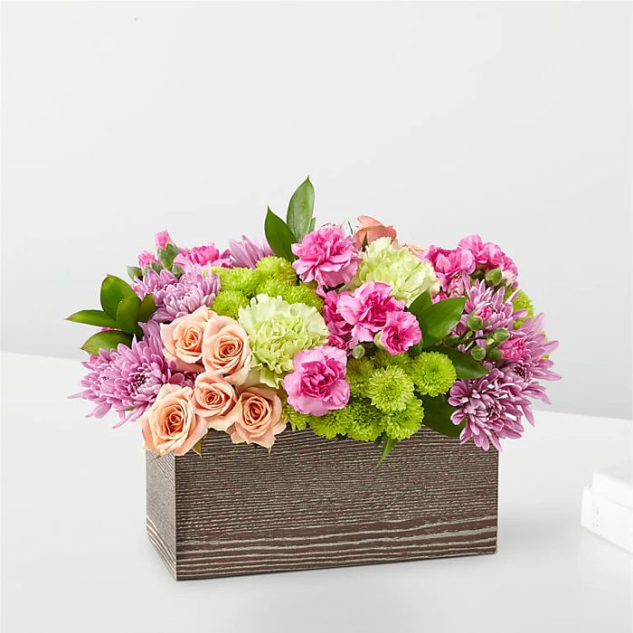 Pink and peach flowers arranged in a rectangular wooden box