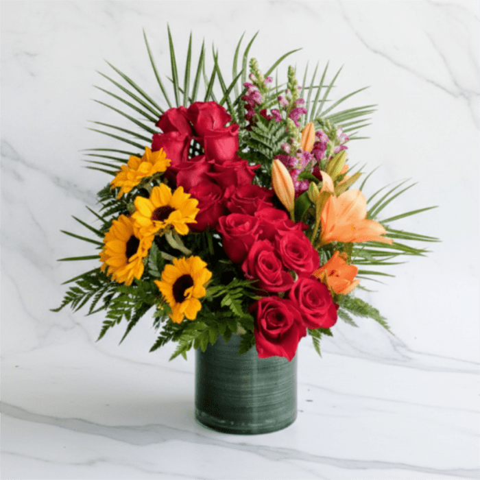 Bouquet of red roses, yellow sunflowers, and orange lilies in a green vase