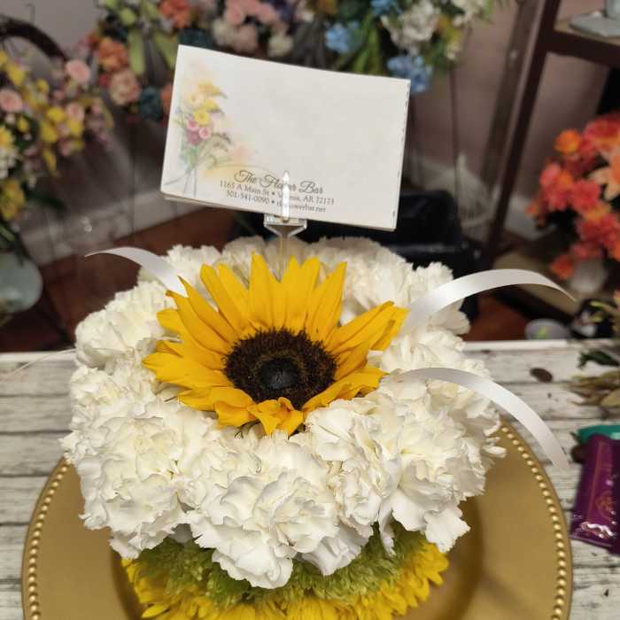 Sunflower and white carnation arrangement on a gold charger plate