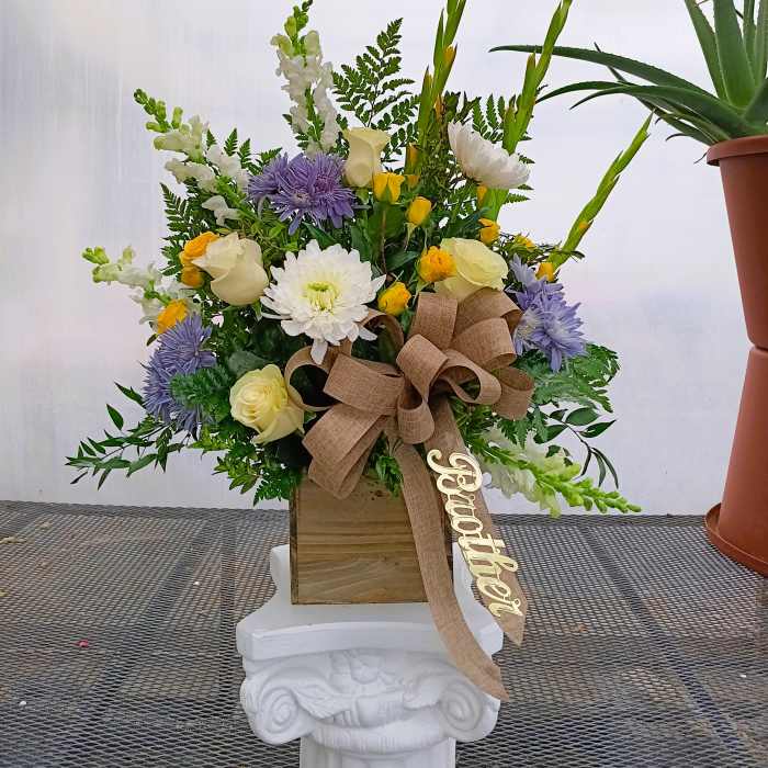Mixed floral arrangement in a wooden box with a large burlap bow