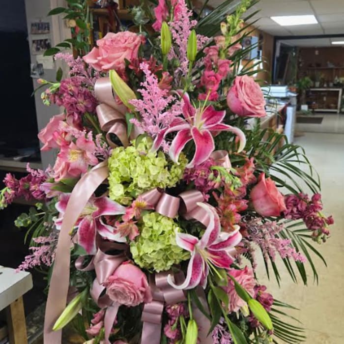 Tall pink floral spray with lilies, roses, and ribbons