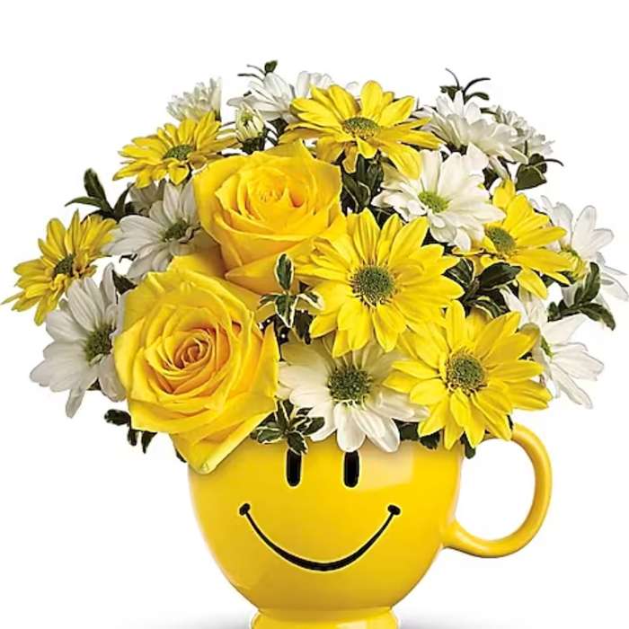 Yellow roses and white daisies in a smiley-face mug