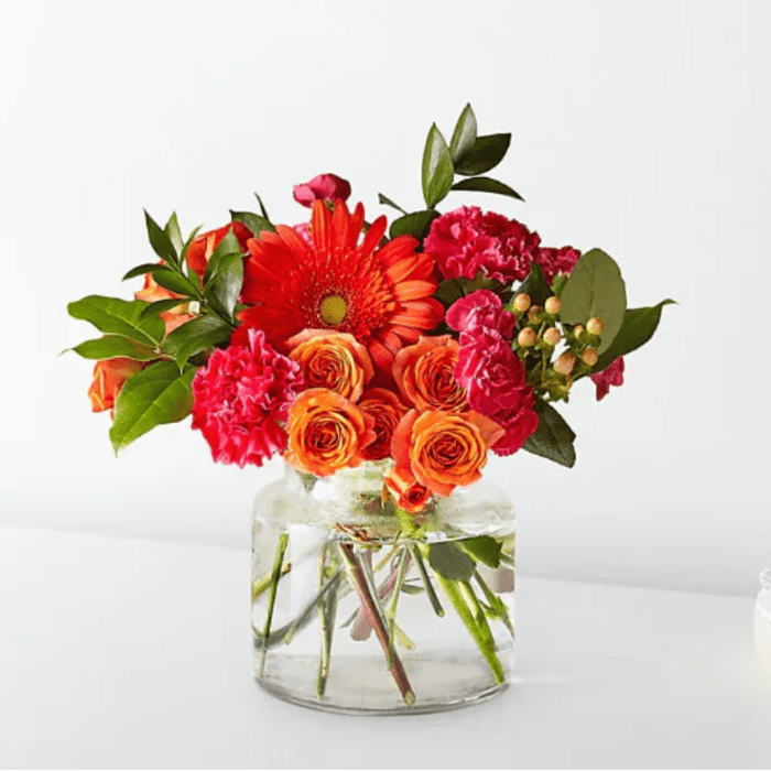 Orange and pink mixed bouquet in a clear glass vase