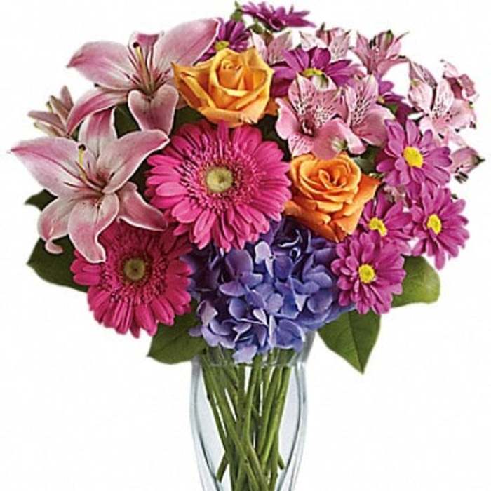 Mixed bouquet of pink lilies, roses, gerbera daisies, and hydrangea in a glass vase