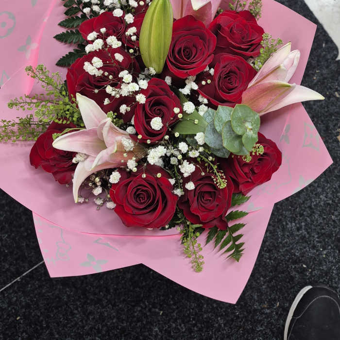 Bouquet of red roses and pink lilies wrapped in pink paper