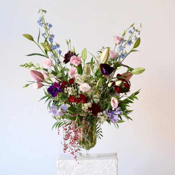 Tall mixed bouquet in a glass vase with pink, red, purple, and blue flowers