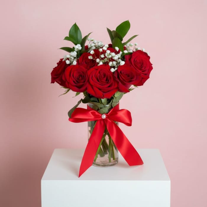 Red roses in a glass vase with a red ribbon bow